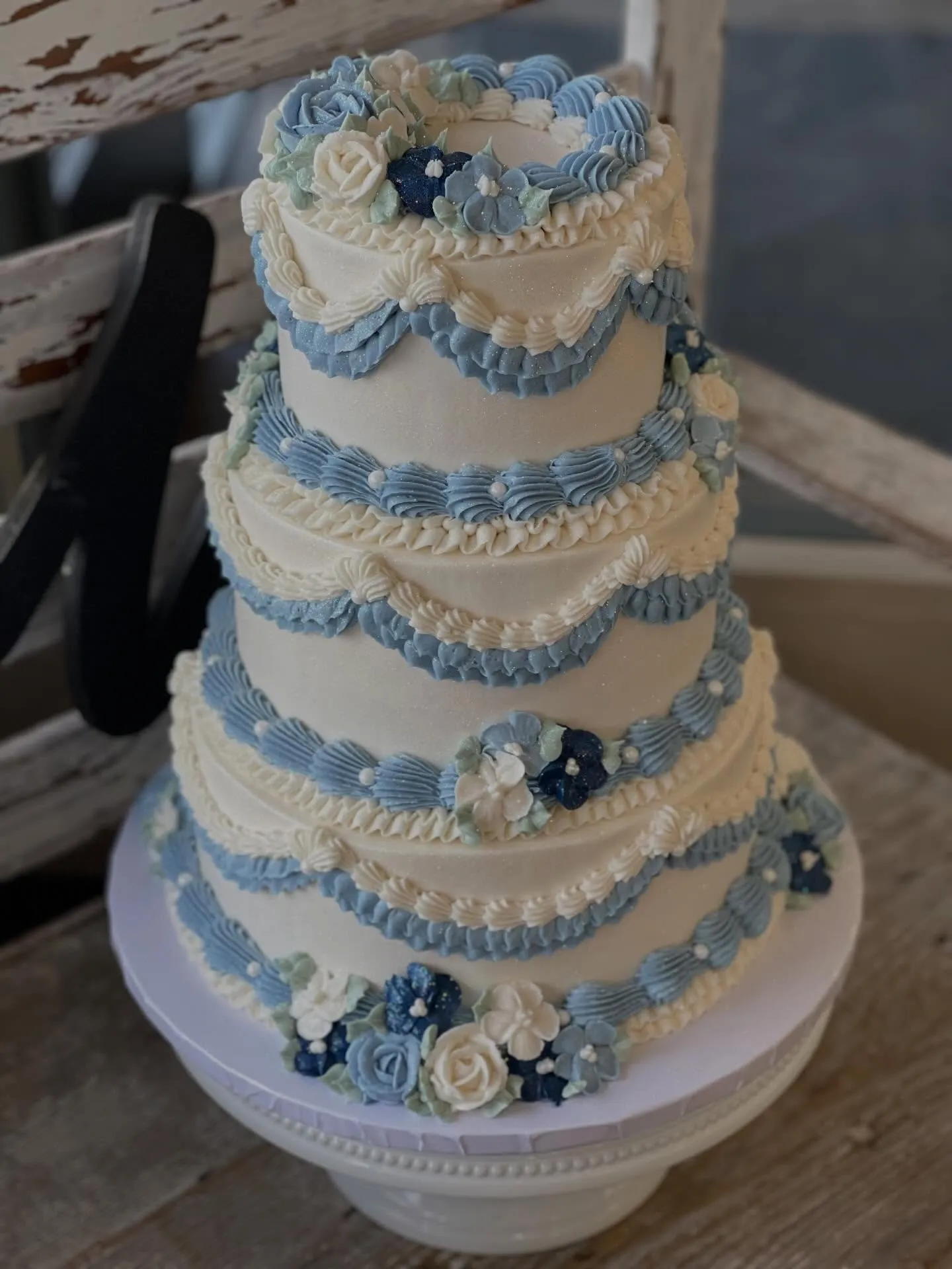 Elegant three-tier wedding cake with gold details and fresh flowers, luxury bakery photography